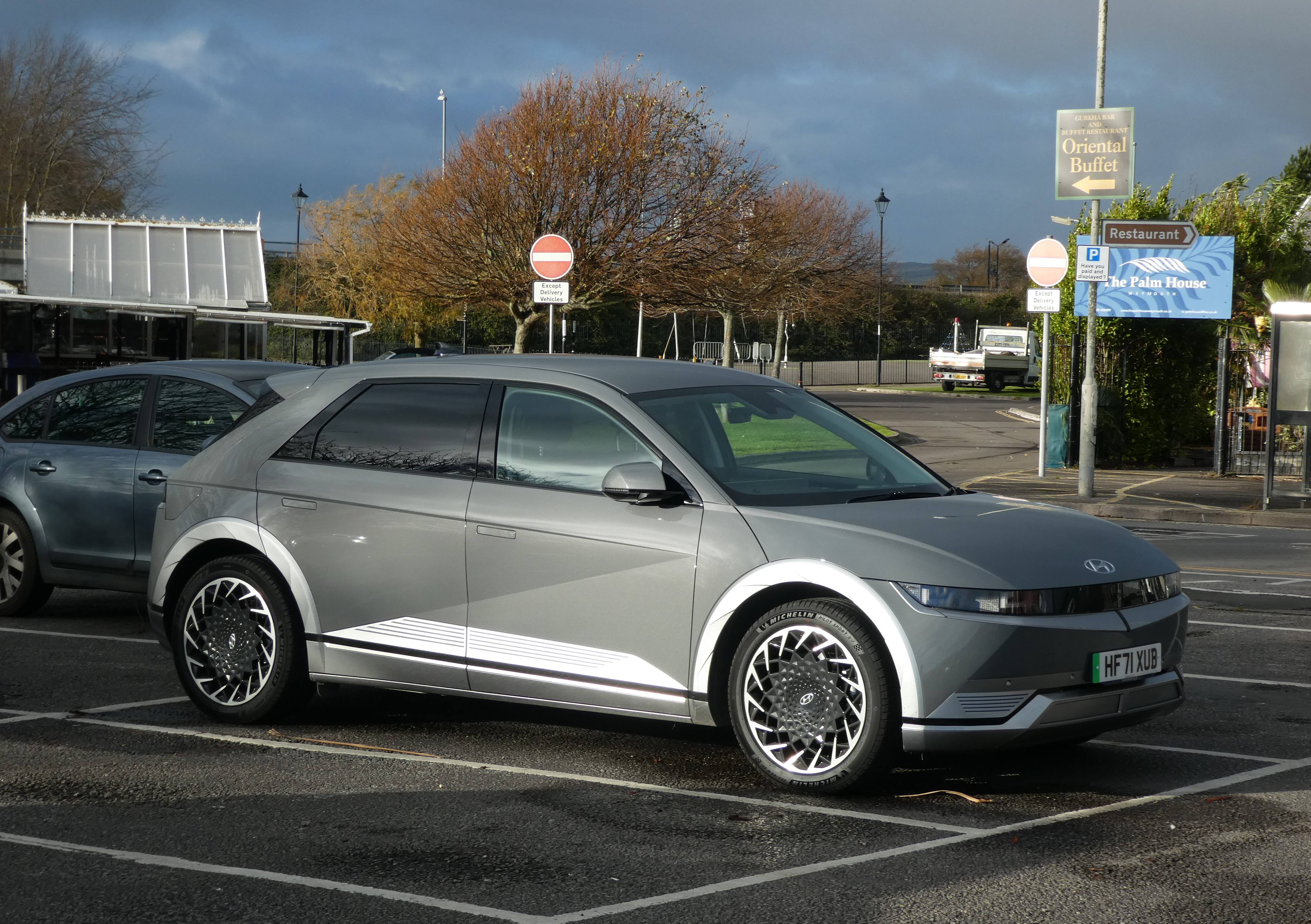 A grey Hyundai Ioniq 5 parked on a street, seen from the front three-quarter view