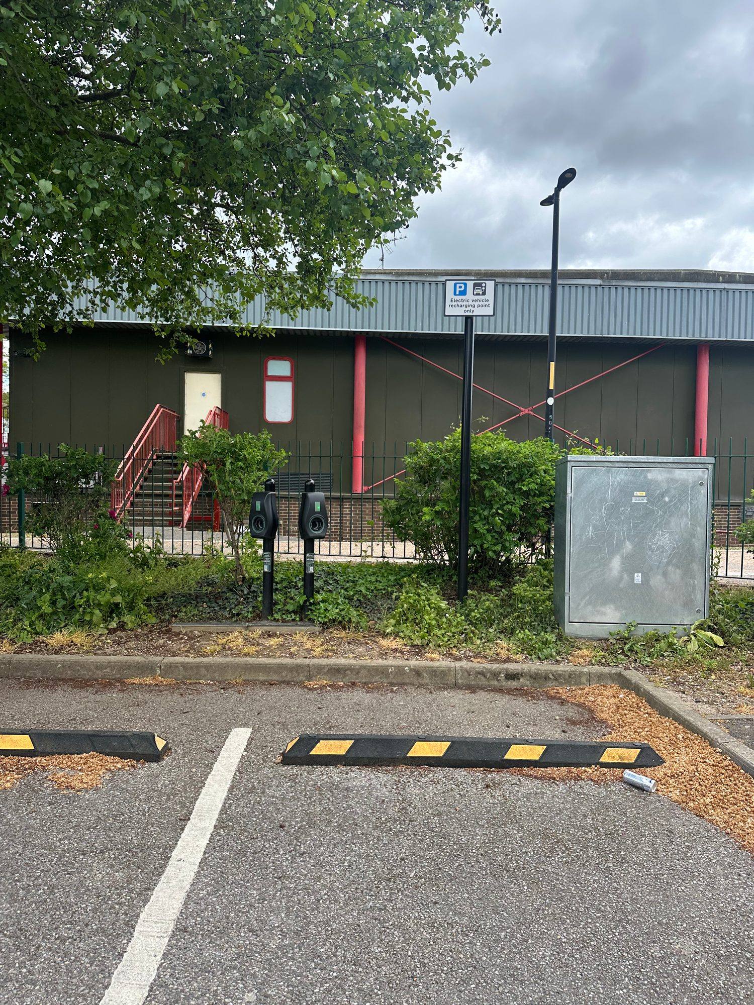 Two black post-mounted Connected Kerb charging points beside an empty parking bay, with a sign reading electric vehicle recharging point only