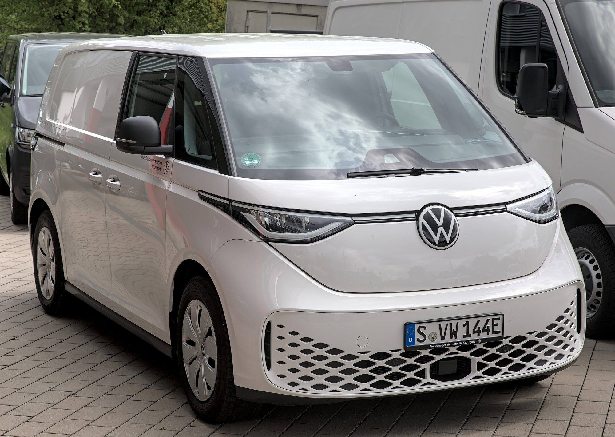 A white Volkswagen ID. Buzz Cargo van parked on paving next to other vans