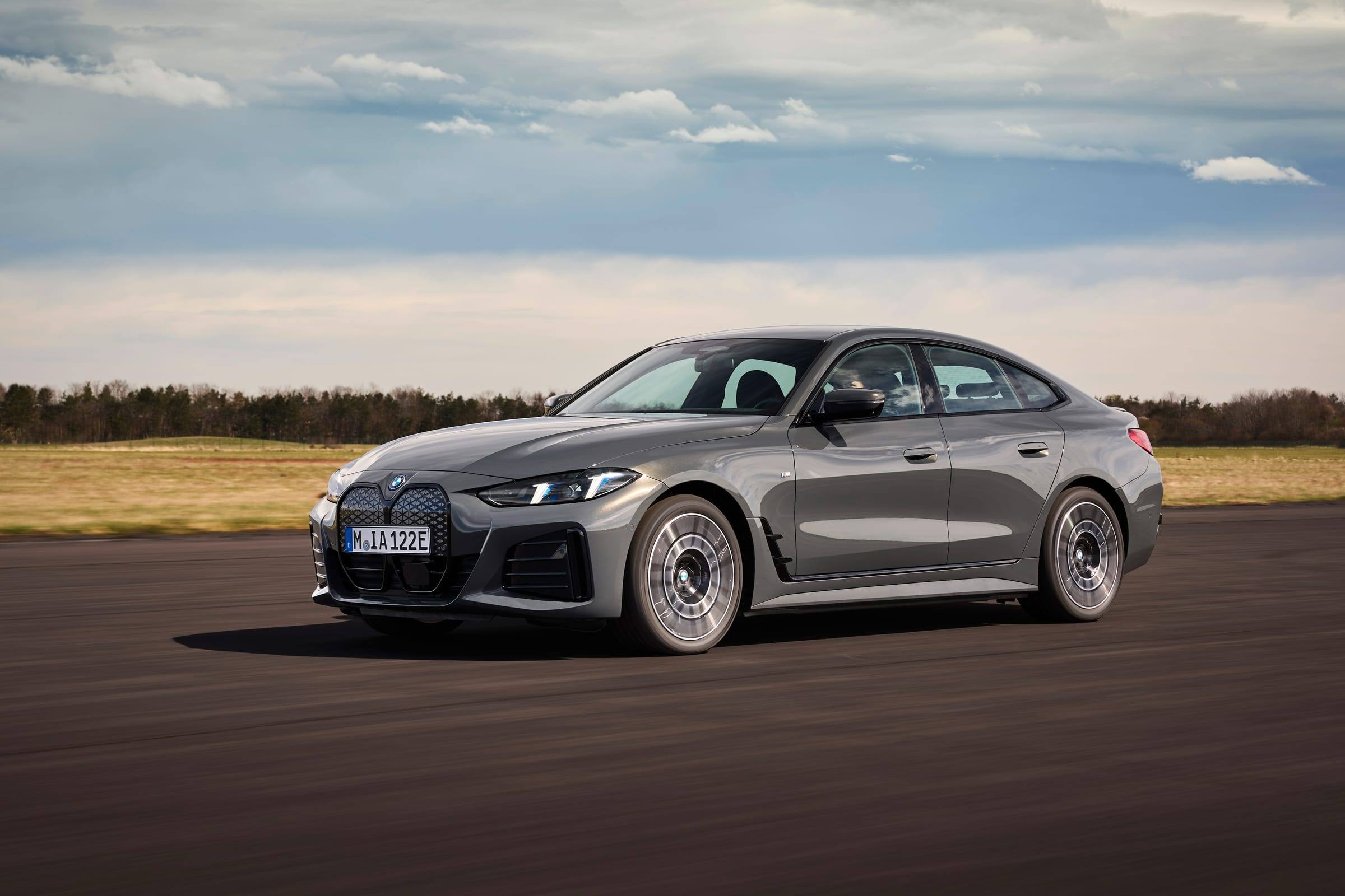 Grey BMW i4 eDrive40, front three-quarter view, driving on an airfield