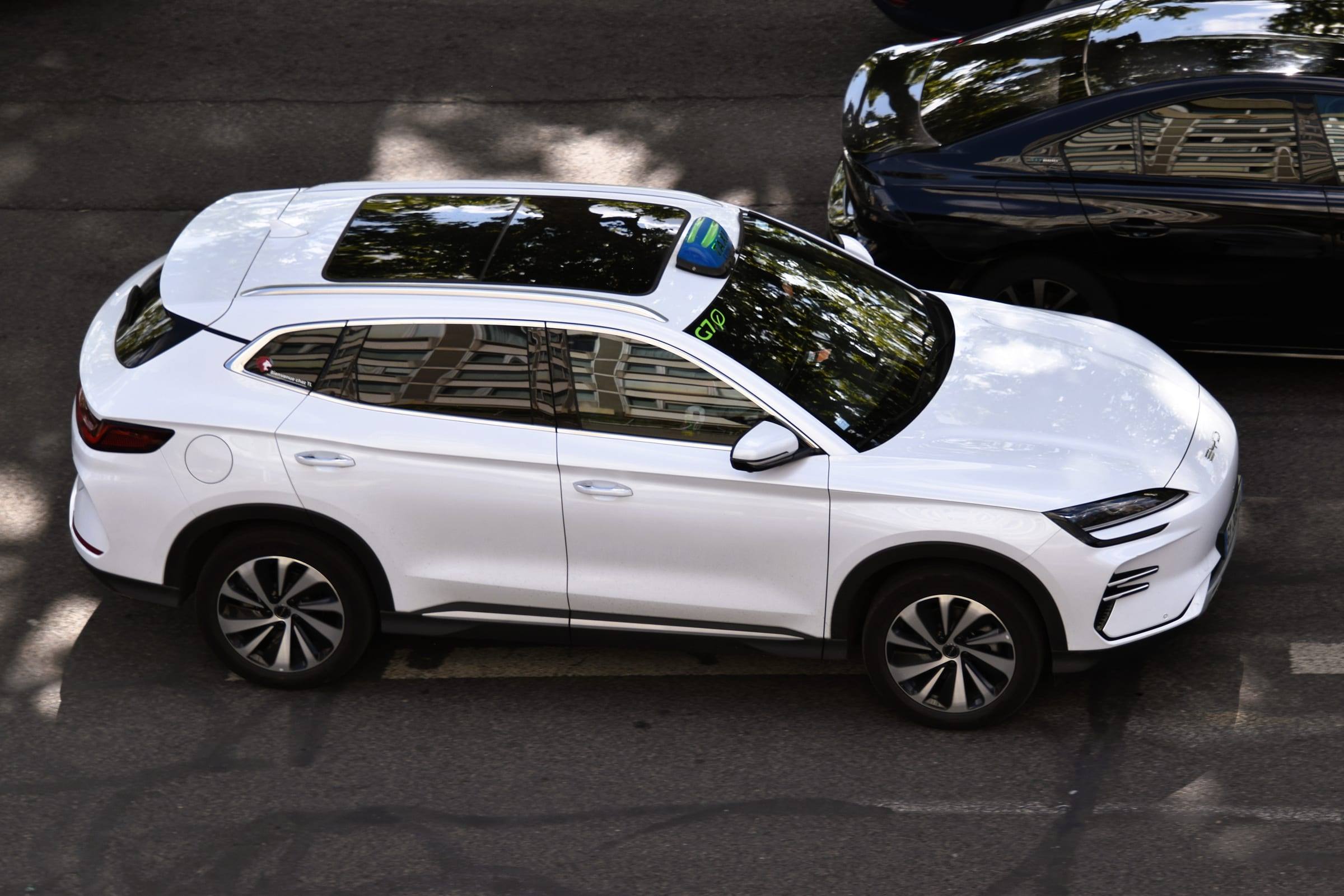 A white BYD Seal U DM-i plug-in hybrid SUV parked on a street, seen from above at the side