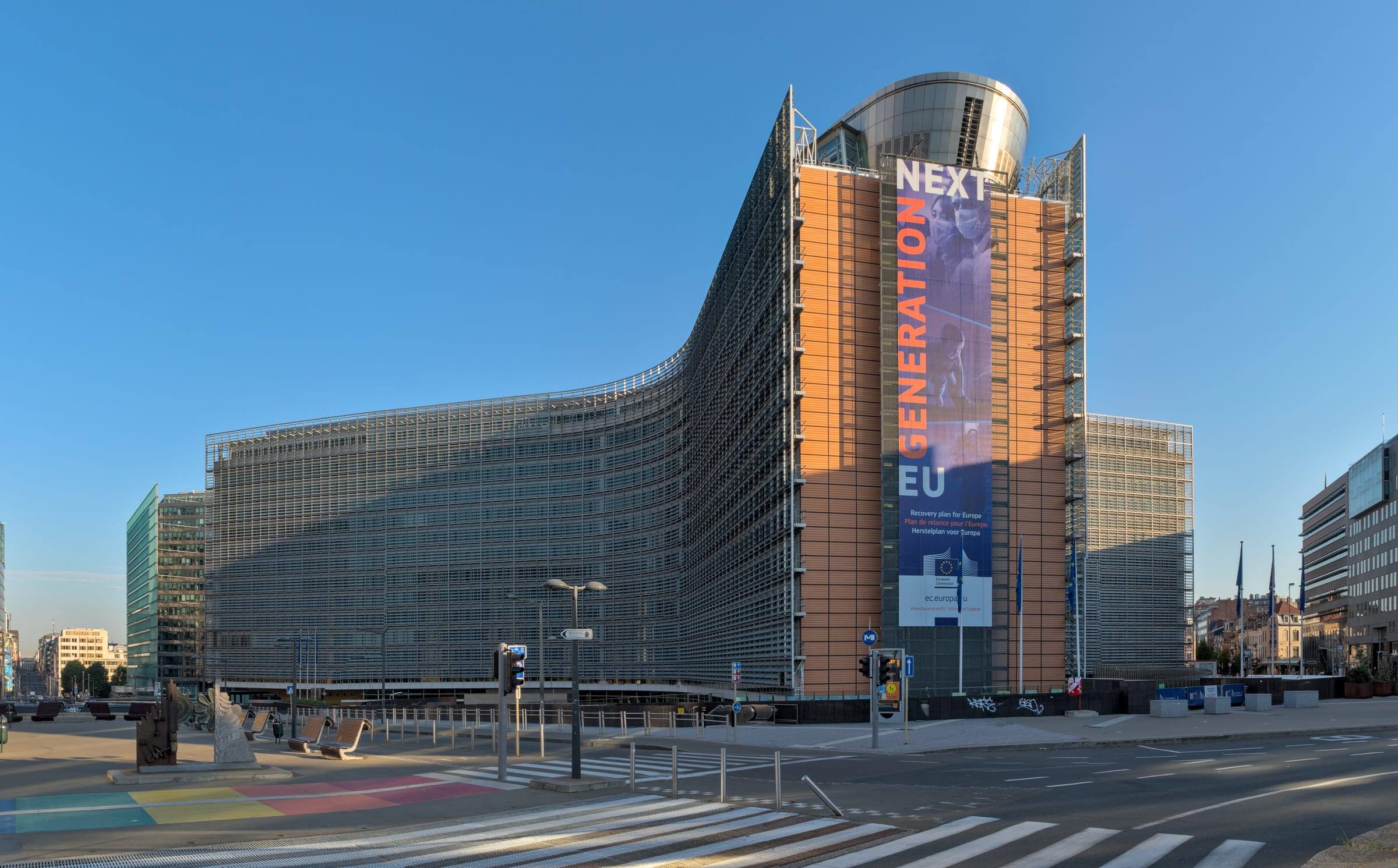 The curved glass facade of the Berlaymont building in Brussels under a clear sky