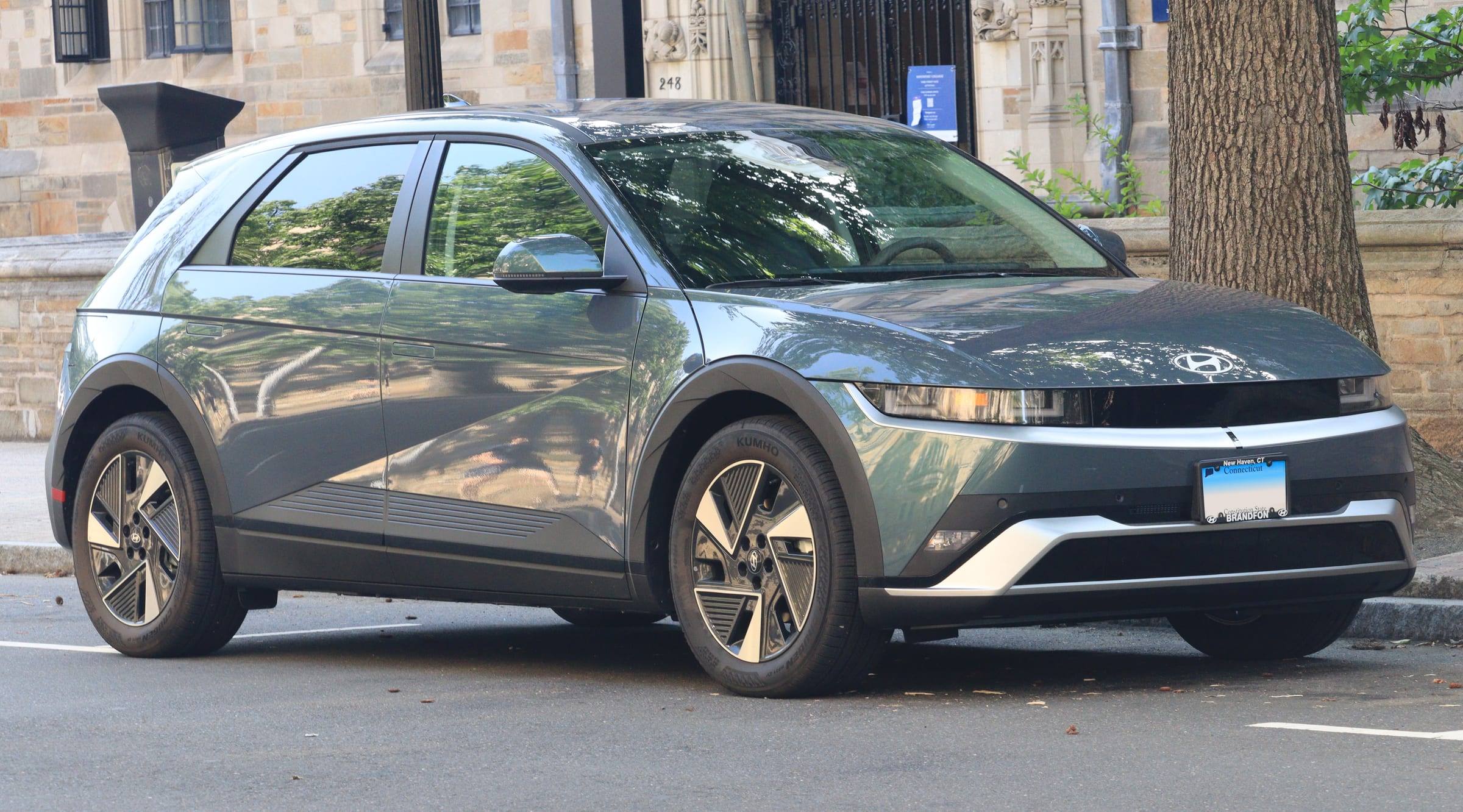 A grey-green 2026 Hyundai Ioniq 5 parked on a city street, seen from the front right