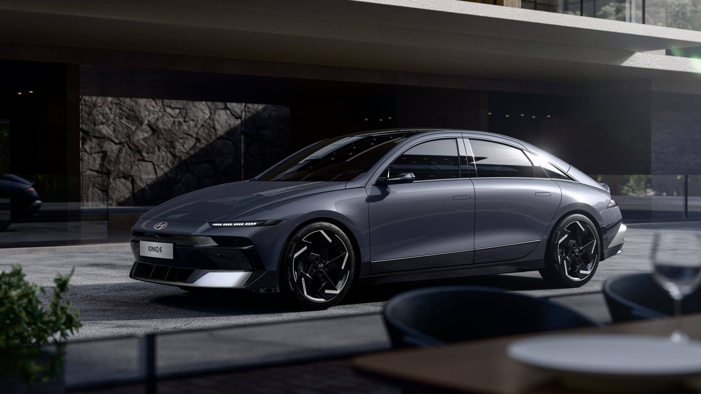 Grey facelifted Hyundai Ioniq 6, front three-quarter view, outside a modern building