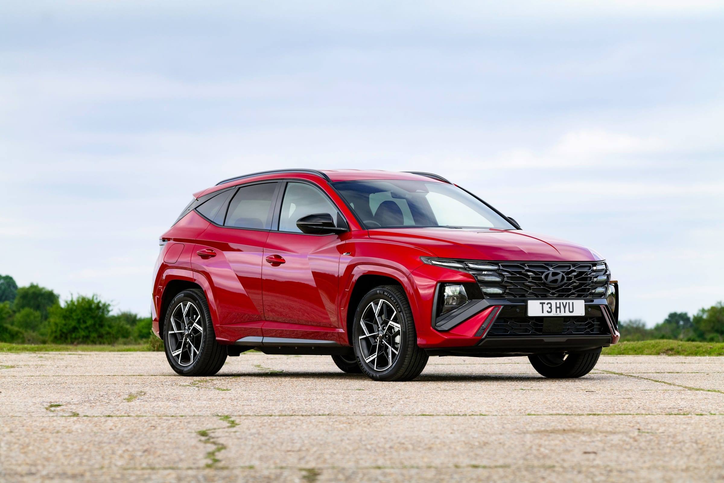 Red Hyundai Tucson N Line, front three-quarter view on an open tarmac area