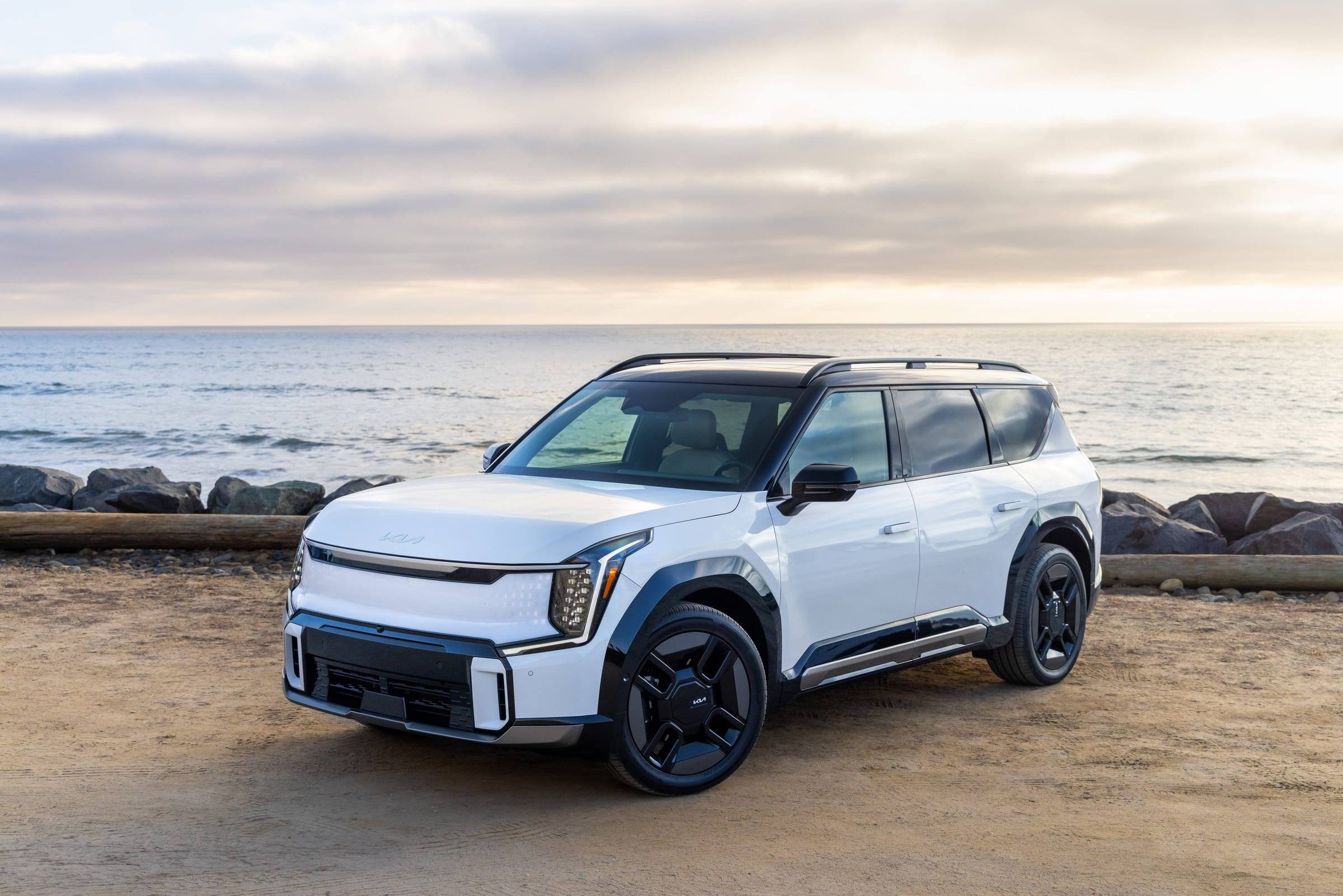 White 2026 Kia EV9, front three-quarter view, parked by the sea