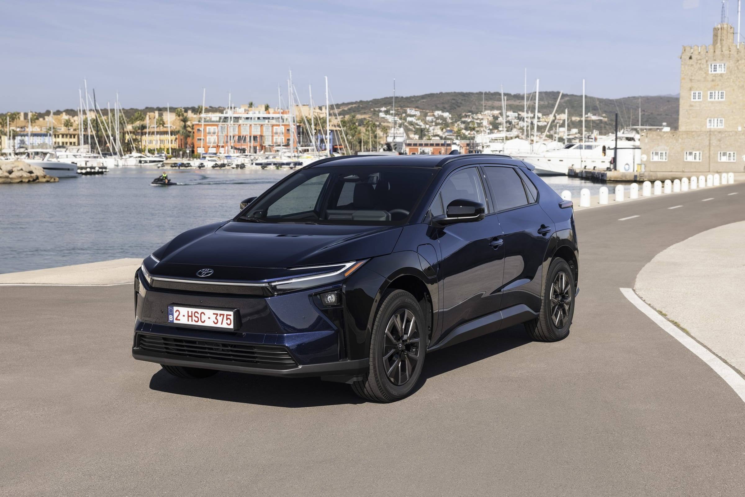 Dark blue 2026 Toyota bZ4X, front three-quarter view, parked by a harbour